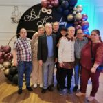 Grupa osób w różnym wieku na tle dekoracji Bal karnawałowy